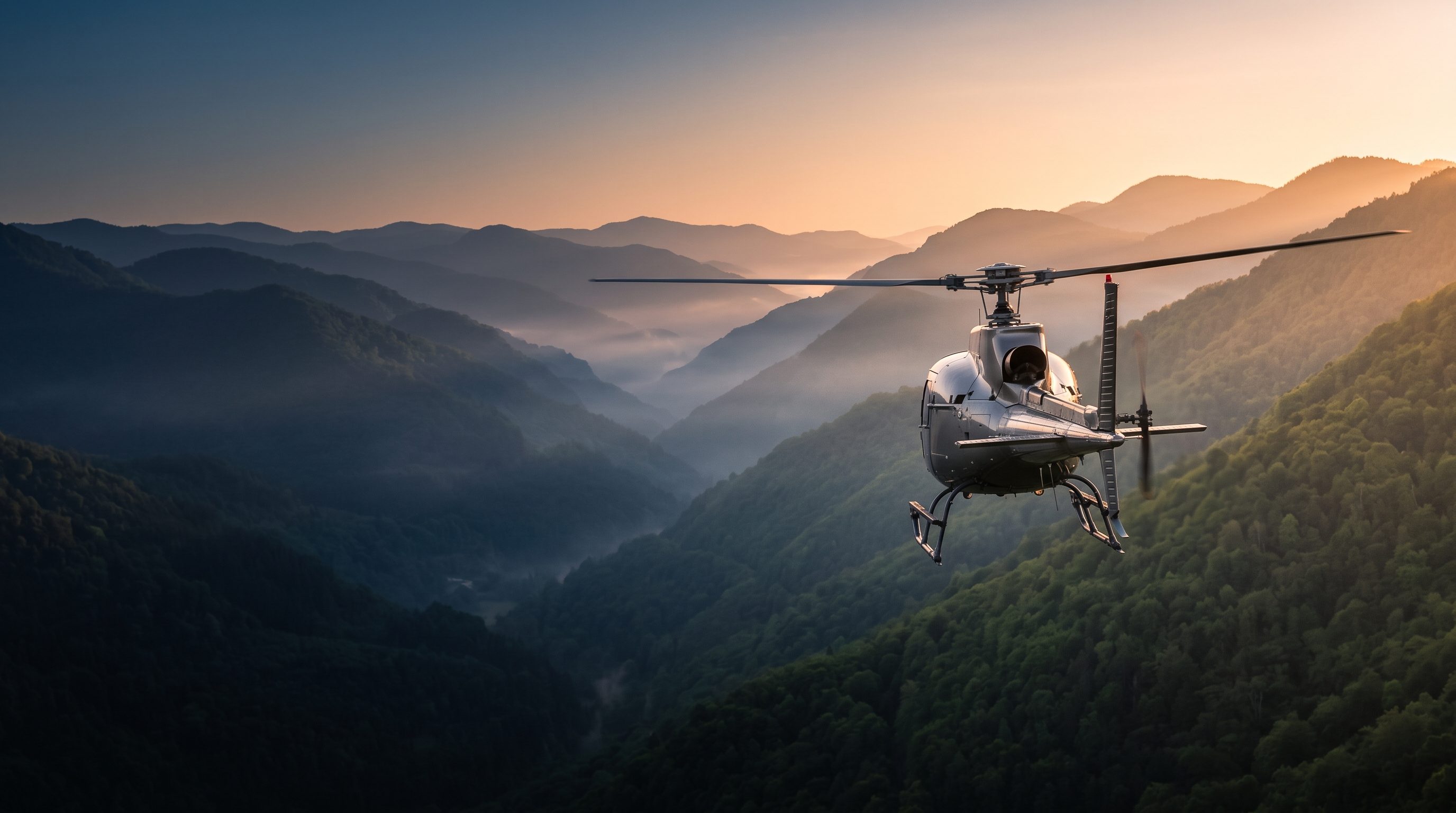 Helicopter flying through a mountain valley at sunrise